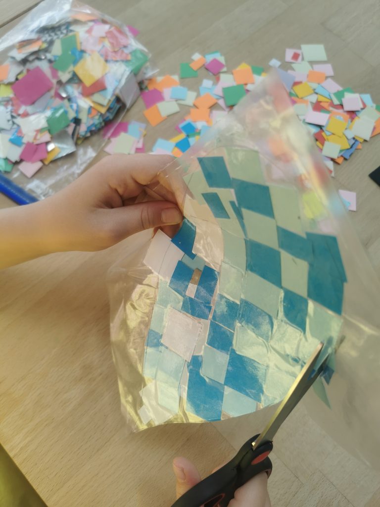 child using scissors to cut heart shape from contact paper