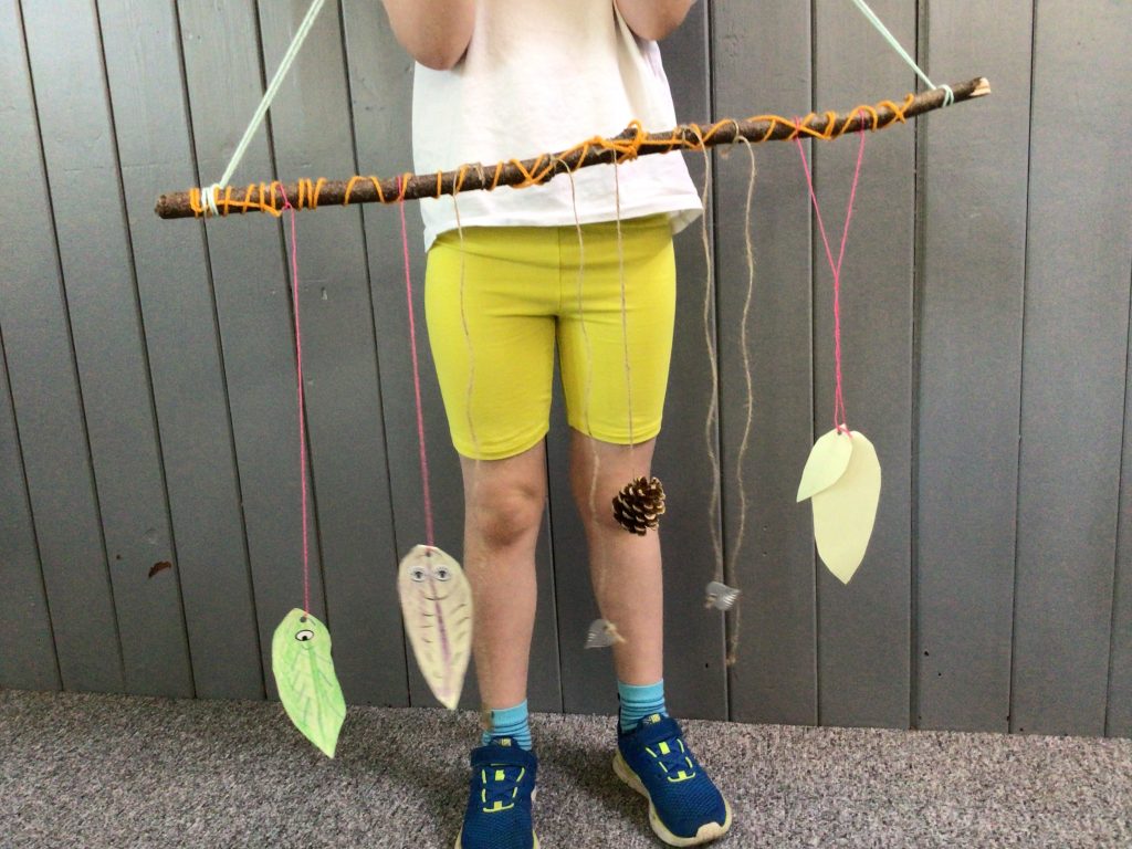 stick wrapped with yarn with decorative objects tied to it