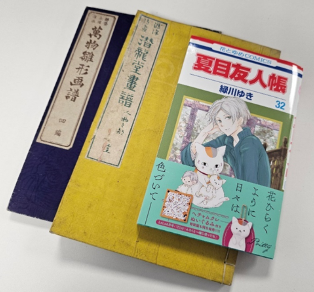 blue and yellow books with Japanese characters stacked with a modern manga book on top