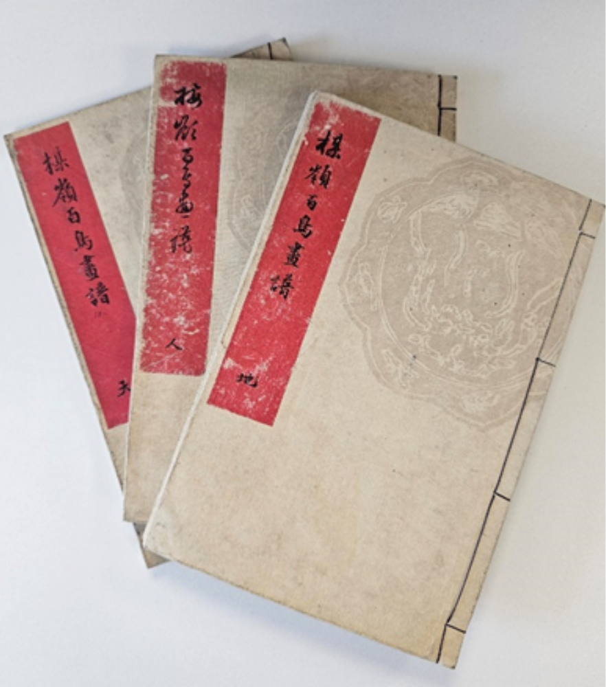 Three pale books with red labels down left hand side with Japanese characters