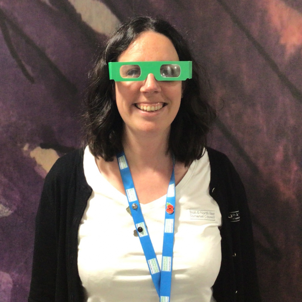 woman with dark hair with blue lanyard and green paper glasses