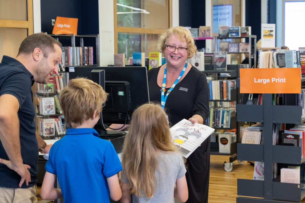 woman in uniform handing book to child