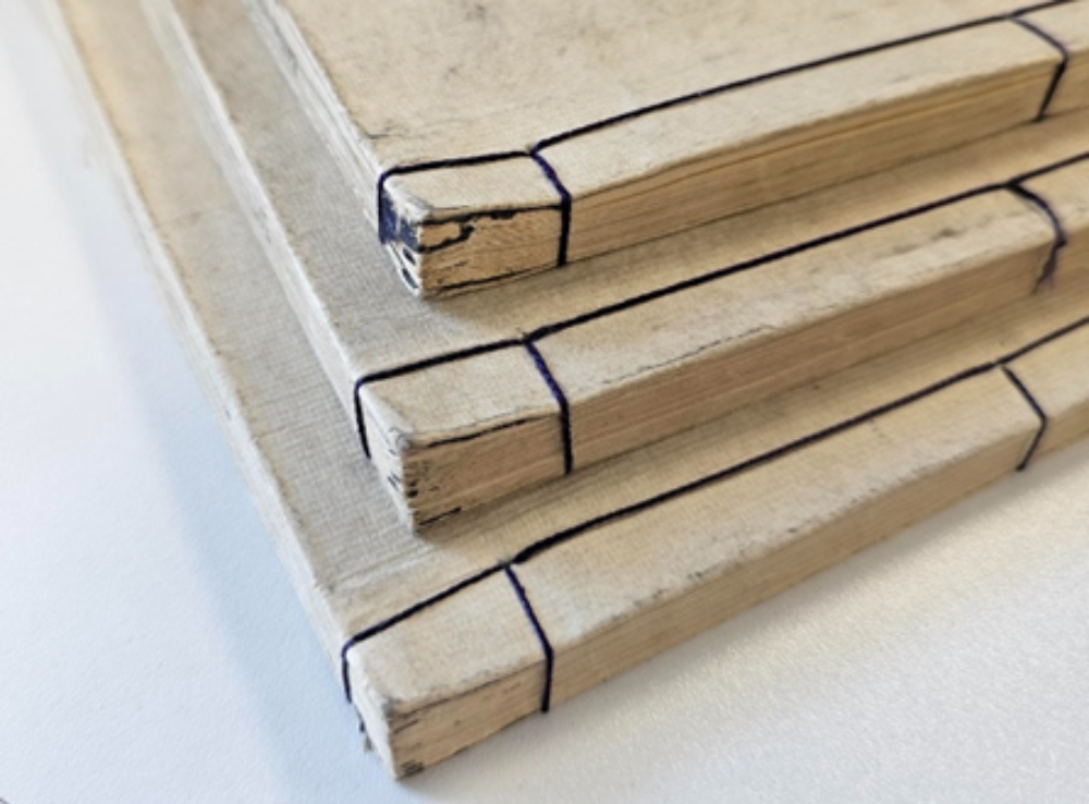 three stacked books with black string binding