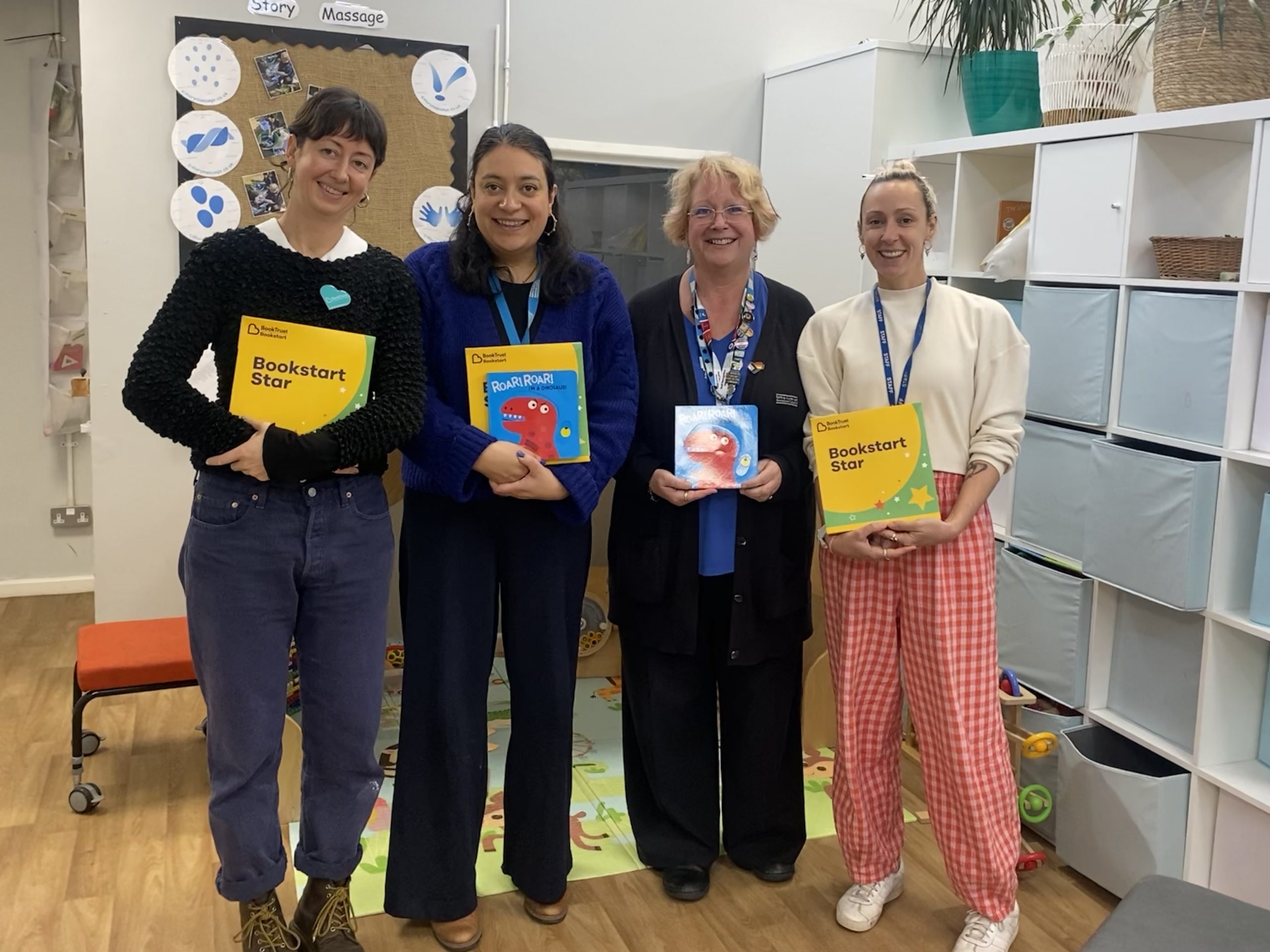 Four women standing and holding book Trust packs smiling at the camera