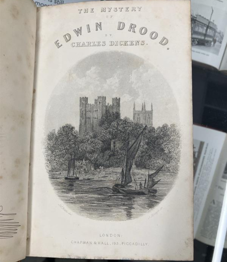 Front page of the Mystery of Edwin Drood. illustration of a boat on a lake in front of a castle.