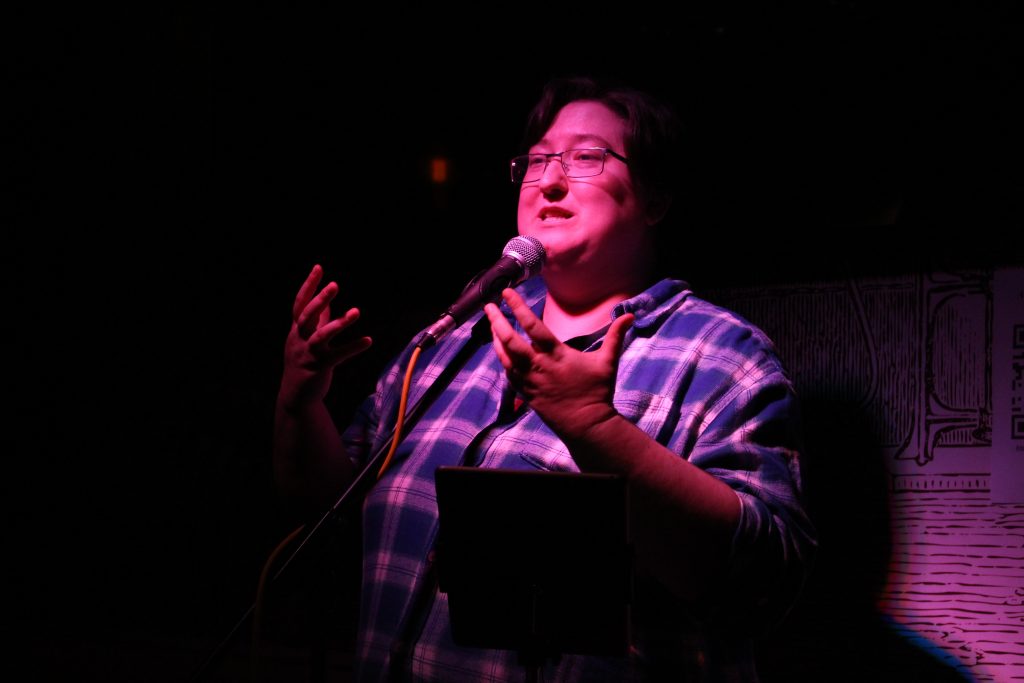 woman stood at a microphone in dramatic purple lighting