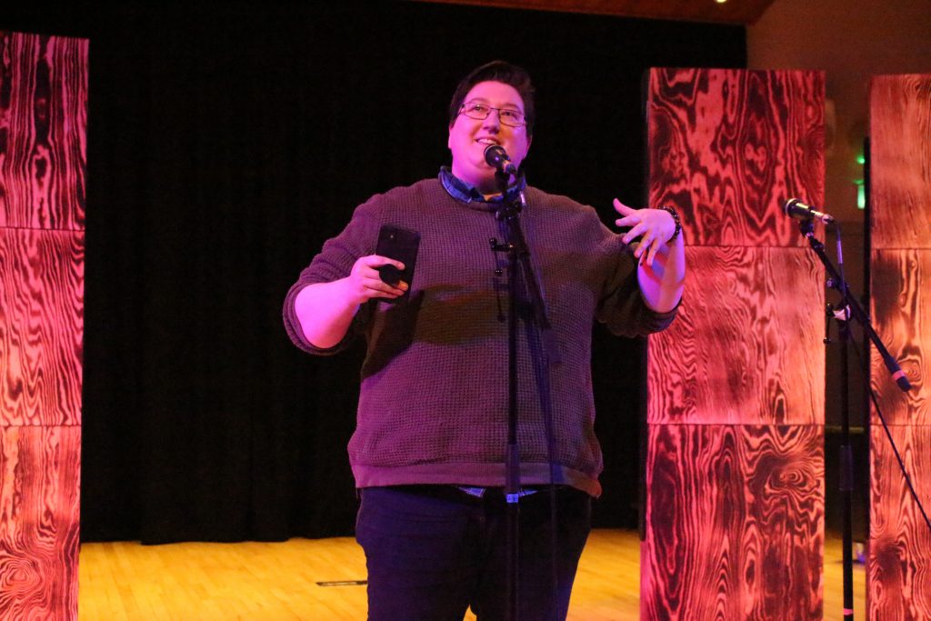 woman stood at a microphone in dramatic purple lighting