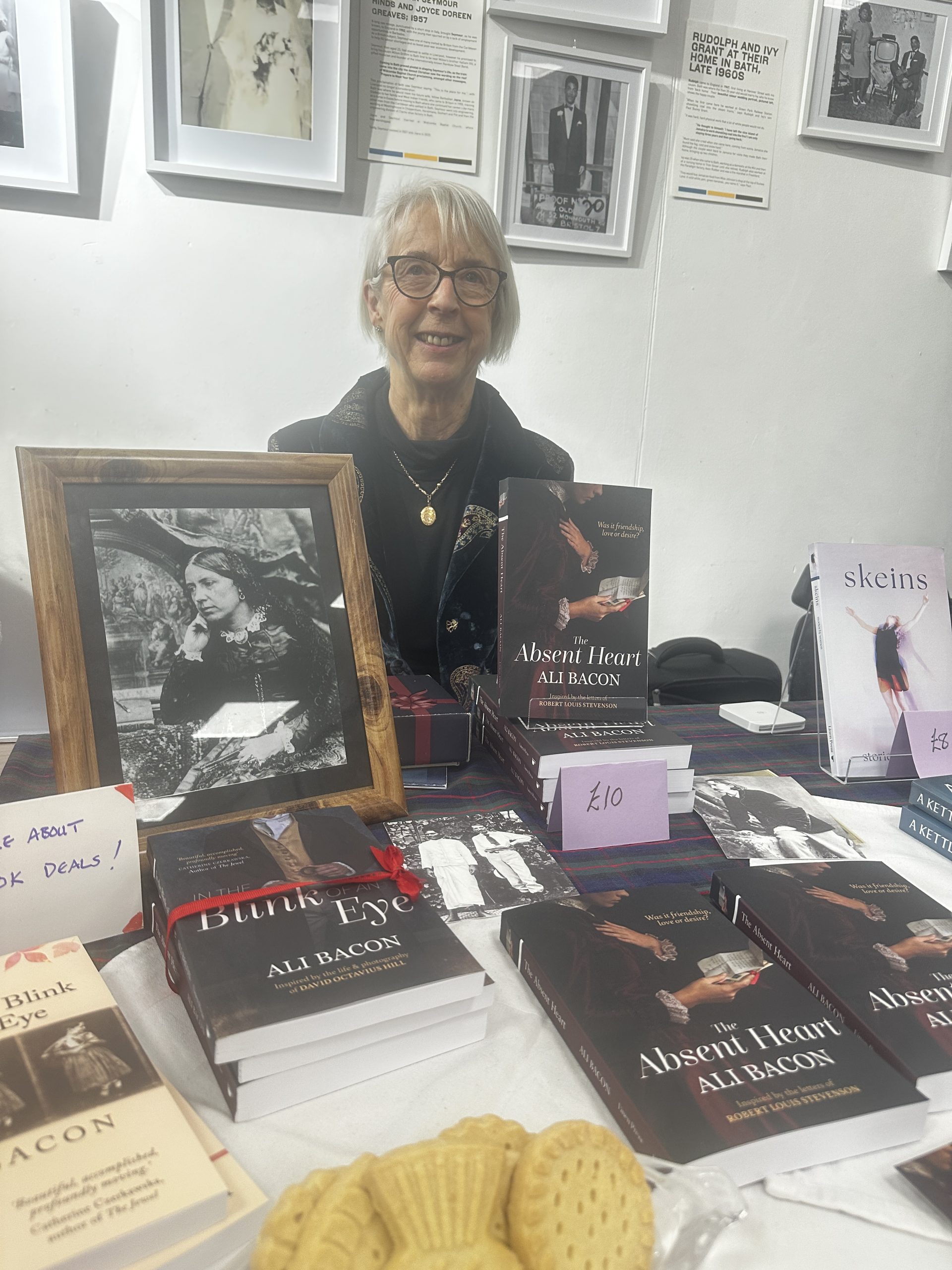Woman sat behind book display with framed photo of Amelia Robertson Hill