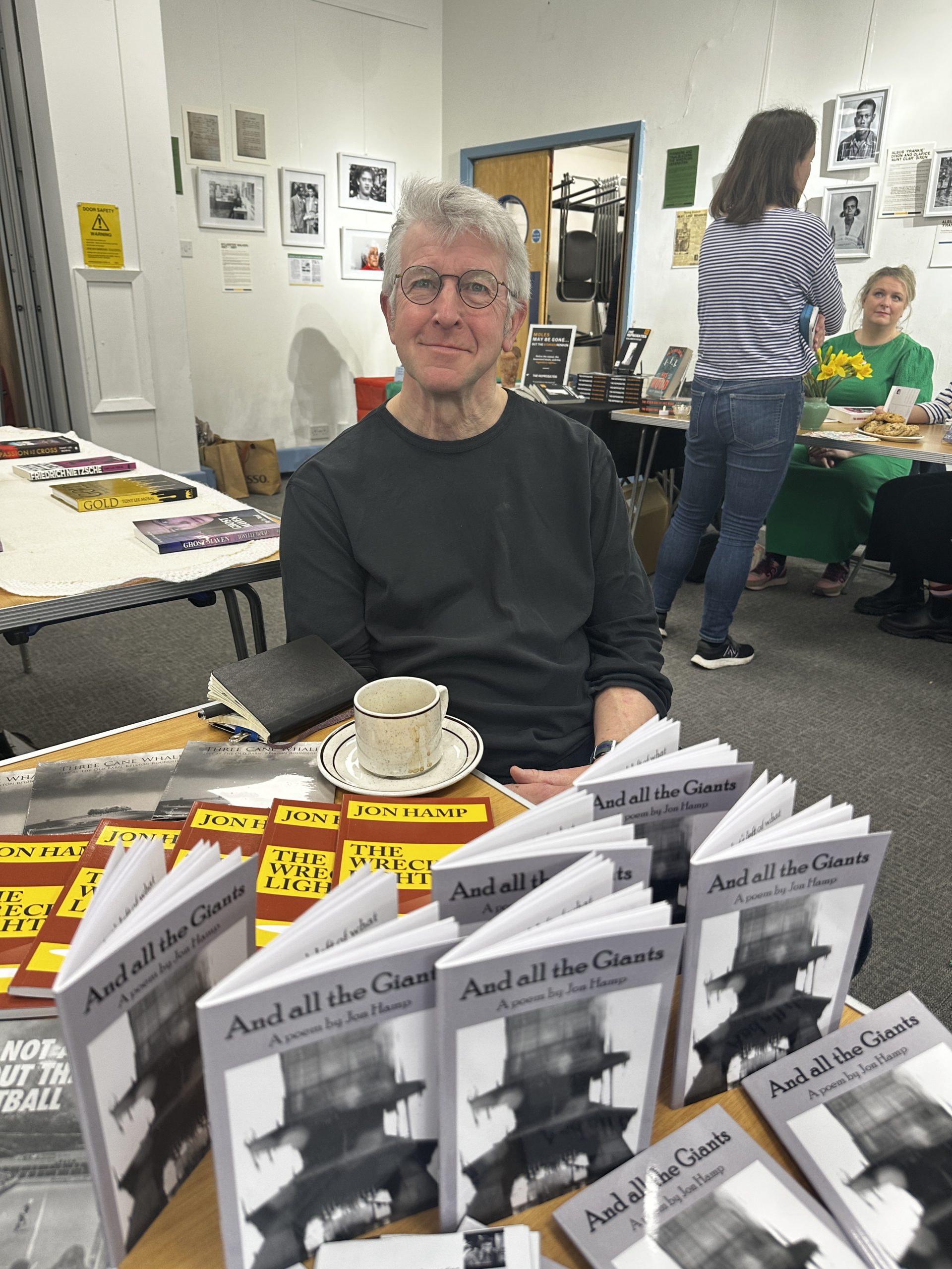 Man sat behind book display with tea cup