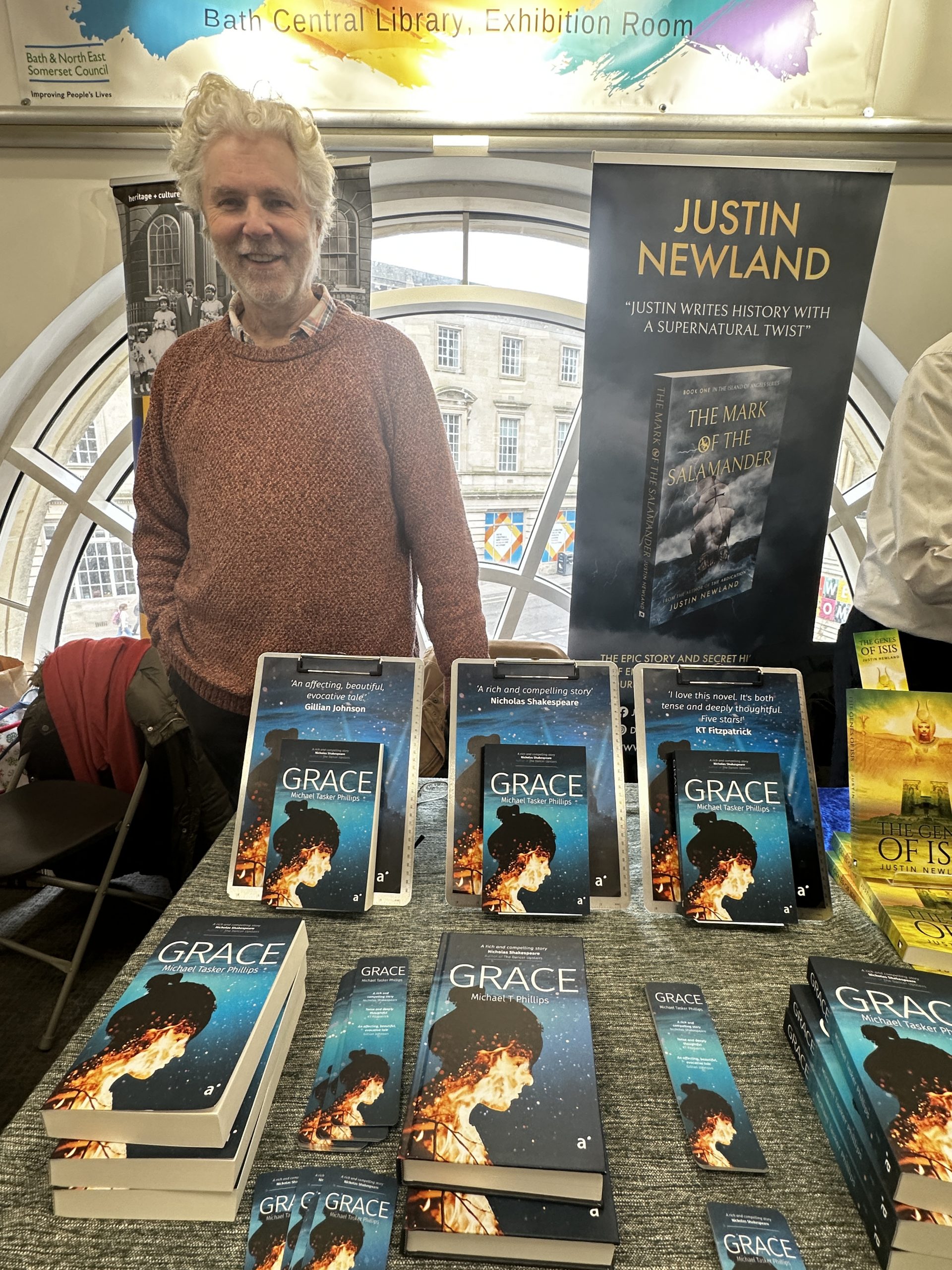 man stood with display of the book 'grace' and 'Justin Newland' banner