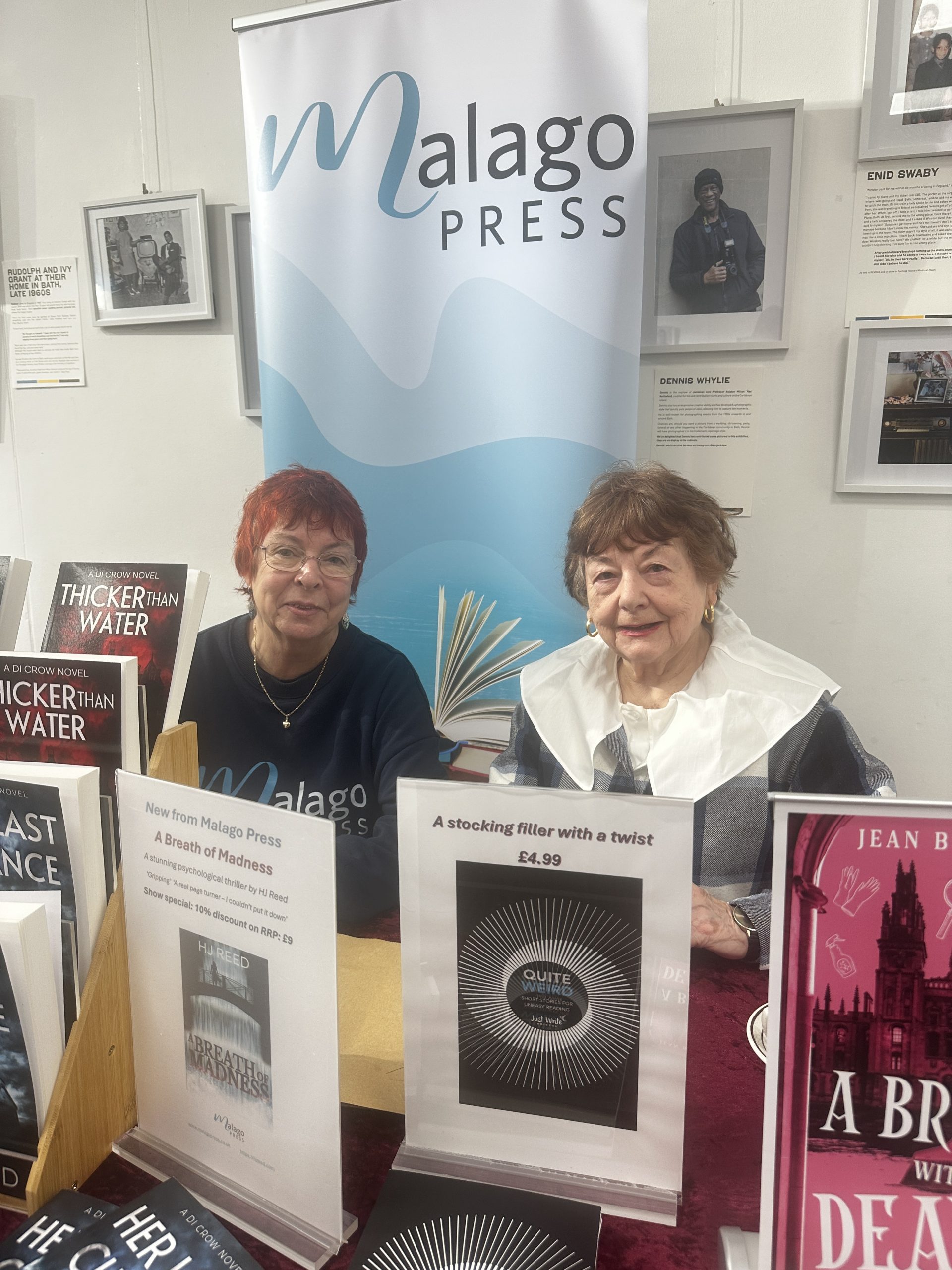 two ladies sat behind display of books with 'Malago Press Pop-up banner behind them