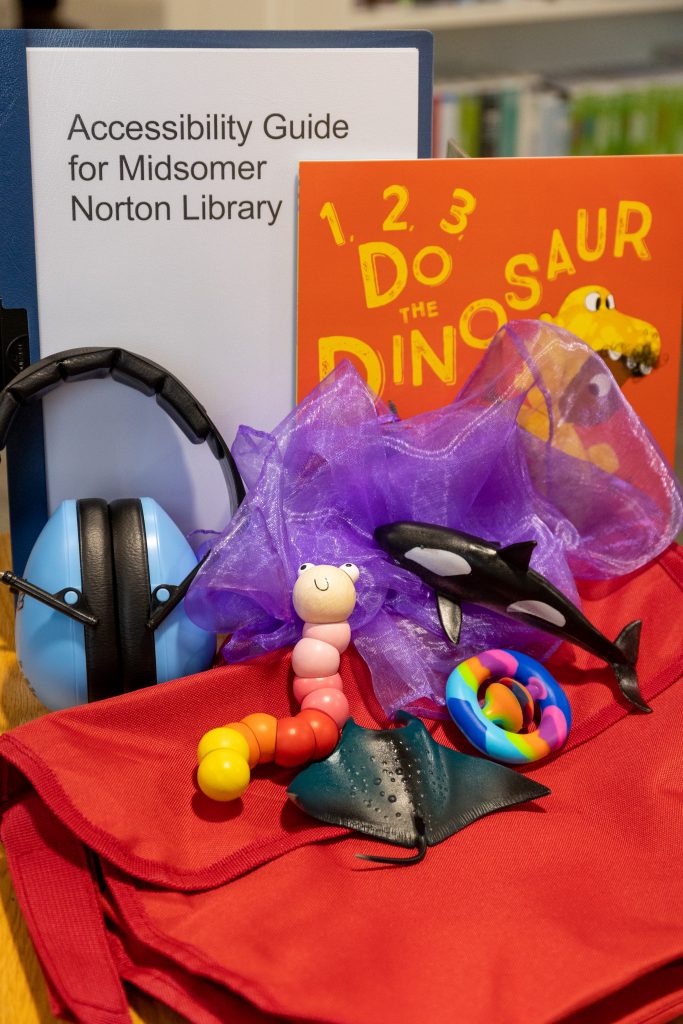 Red Sensory Explorer Bag with ear defenders, fidget toys, a guide to the library and book