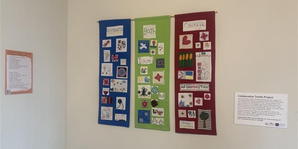 Three textile pieces on display on a white wall